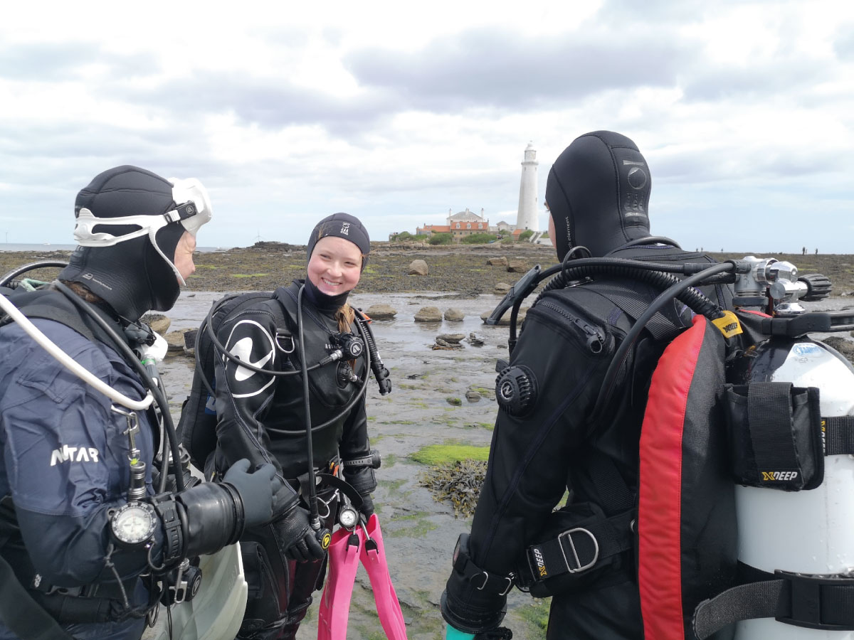 Three eco-divers smiling during a debrief, emphasizing the importance of psychological safety in diving.