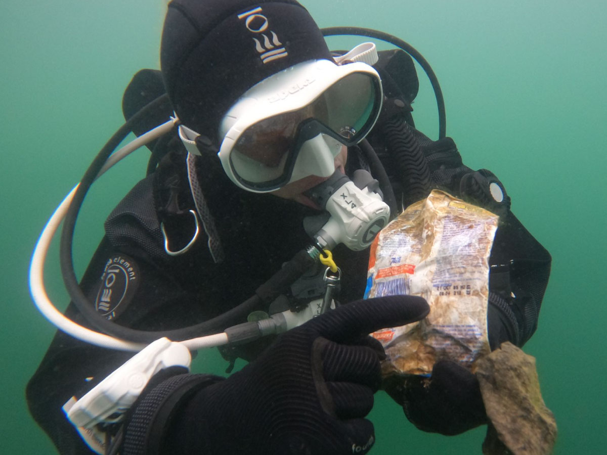 Diver holding a crisp packet found during a Dive Against Debris, showcasing the importance of eco-diving.